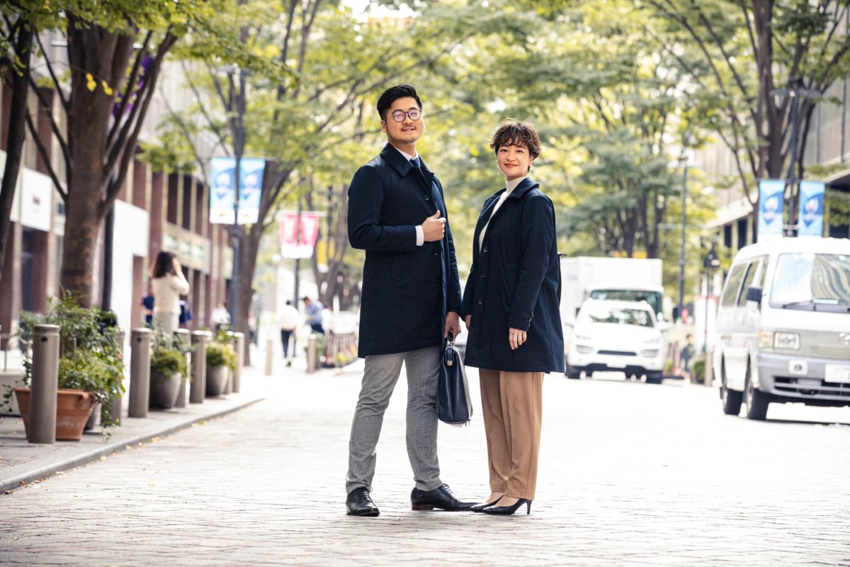 カポック中わたのコートを着た男女が冬の都市の並木道に立つ様子